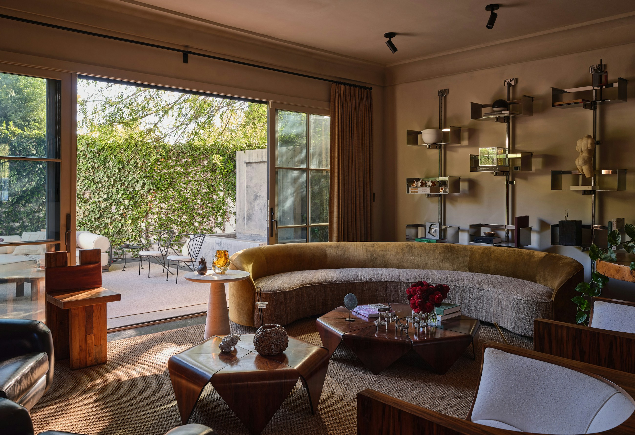 West Hollywood living room with a curved velvet sofa, faceted wood table, and brass shelving